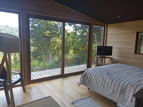 a bedroom with a bed and a balcony with a television at Bienvenidos a su refugio Chiloé in Castro