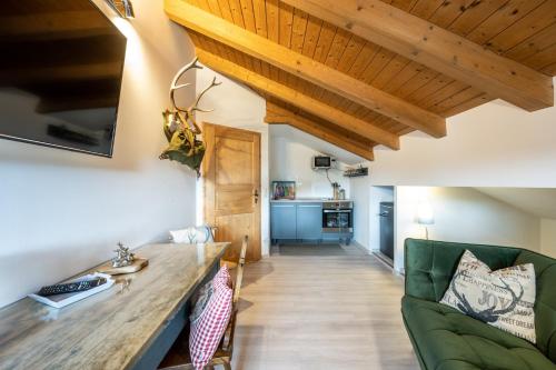 a living room with a green couch and wooden ceilings at Ferienwohnung Alpensonne in Oberstdorf