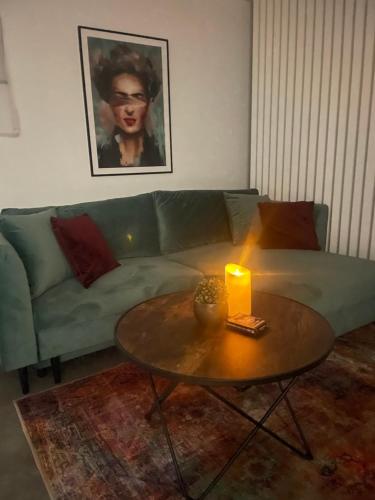 a living room with a green couch with a candle on a table at Secret Garden Vendégház in Pécs