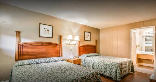 a hotel room with two beds and a mirror at Economy Hotel Drayton in Drayton