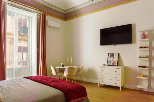ein Schlafzimmer mit einem Tisch und einem TV an der Wand in der Unterkunft Le Volte And Suite in Catania