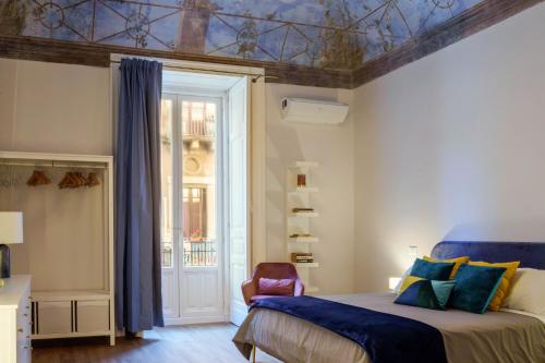 Schlafzimmer mit einem Bett mit blauer Bettwäsche und einem Fenster in der Unterkunft Le Volte And Suite in Catania