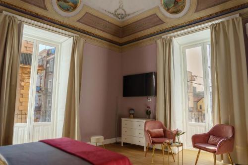 a bedroom with a bed and two chairs and a tv at Le Volte And Suite in Catania