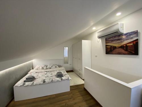 1 dormitorio blanco con 1 cama y una pintura en la pared en Apartman Marsalforn, en Veternik