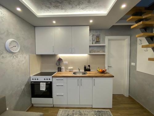 una cocina con armarios blancos y fregadero en Apartman Marsalforn, en Veternik