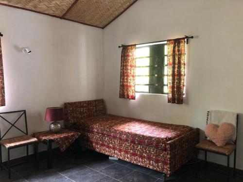 a bedroom with a bed and two chairs and a window at Karamaluu Garden Lodge in Gunjur