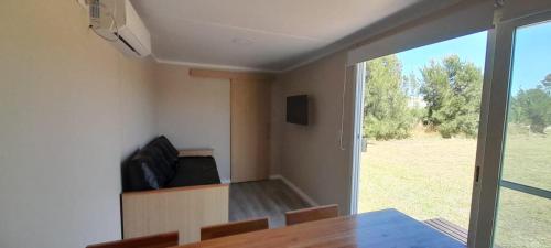 une salle à manger avec une table et une vue sur un champ dans l'établissement Casas Containers - Barrio Los Teros con pileta compartida - Santa Clara del Mar, à Santa Clara del Mar