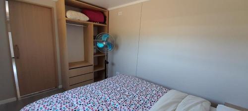 a small bedroom with a bed and a fan at Casas Containers - Barrio Los Teros con pileta compartida - Santa Clara del Mar in Santa Clara del Mar