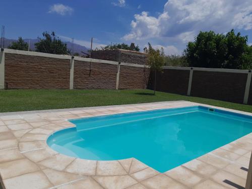 a blue swimming pool in a yard with a fence at Hermosa casita con quincho y amplia pileta TODAS LAS COMODIDADES Paz total in Ullún