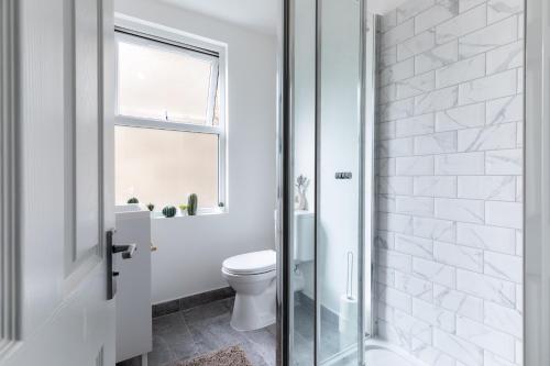 baño blanco con aseo y ventana en Homely 3 Bedroom House in Hammersmith, en Londres