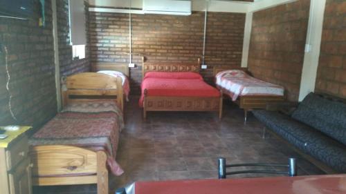 a room with four beds and a couch at Hermosa casita con quincho y amplia pileta TODAS LAS COMODIDADES Paz total in Ullún
