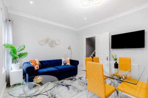 a living room with a blue couch and yellow chairs at Homely 3 Bedroom House in Hammersmith in London