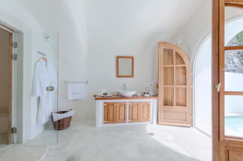 a white bathroom with a sink and a mirror at Perivolas Hotel in Oia