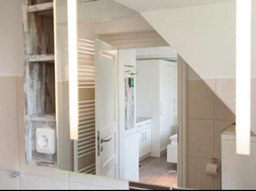 a bathroom with a staircase and a bathroom with a mirror at Ual Öömrang Wiartshüs in Norddorf