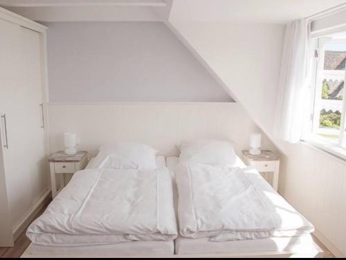 a white bed with white sheets and pillows in a bedroom at Ual Öömrang Wiartshüs in Norddorf