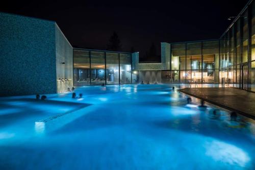a swimming pool at night in front of a building at Appartement spacieux au centre de la Gruyère in Broc