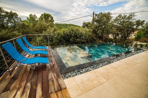 - une piscine avec deux chaises à côté d'une terrasse en bois dans l'établissement VILLA PISCINE MIROIR ET JACUZZI, à Saint-Bauzille-de-Montmel