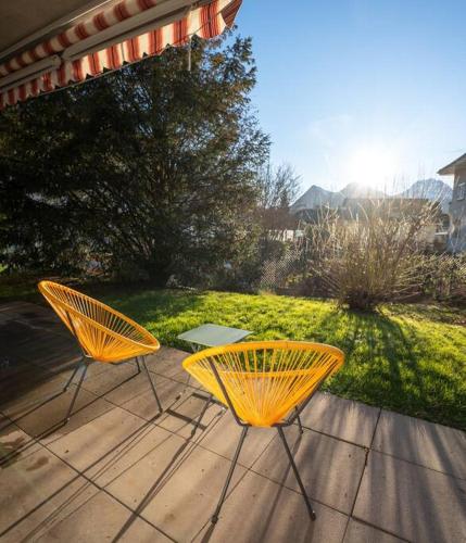 two yellow chairs and a table on a patio at Appartement spacieux au centre de la Gruyère in Broc