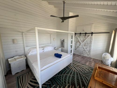 a bedroom with a white bed and a ceiling at Barbuda Cottages in Codrington Village
