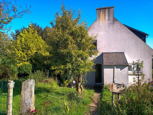 uma velha casa branca com uma árvore e uma cerca em Maison d'hôte de l'Aber - Sable em Crozon