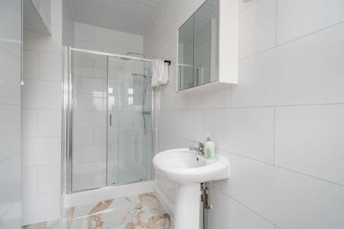 uma casa de banho branca com um lavatório e um chuveiro em Spacious 2bed Brick Lane flat - 2nd Floor em Londres