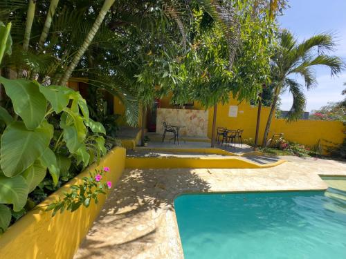 a pool in a yard with trees and a yellow wall at Encomendero Hotel -Centro Histórico- in Santa Fe de Antioquia