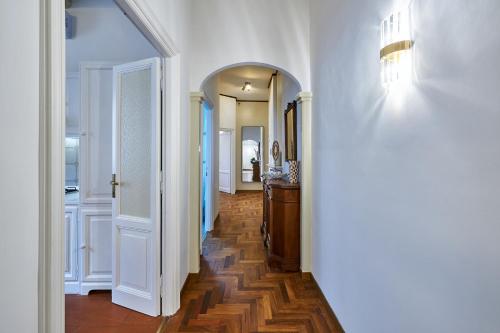 einen Flur mit weißen Wänden, Holzböden und einem Spiegel in der Unterkunft IREX Vatican private apartment in Rom