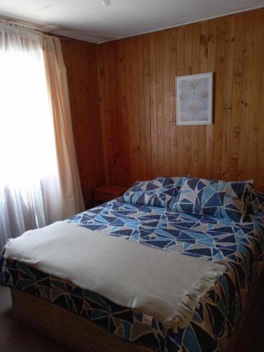 um quarto com uma cama azul em Cabañas Ancud Magico em Ancud