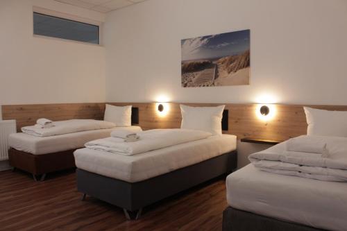Habitación con 3 camas y almohadas blancas. en Hive Apartments - direkt an der Hannover Messe, en Hannover