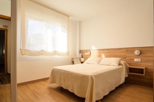 a bedroom with a large bed with a window at Pensión Casa Alvarito in Portonovo