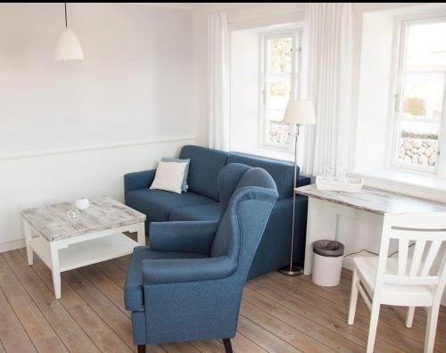 a living room with a blue chair and a table at Ual Öömrang Wiartshüs in Norddorf