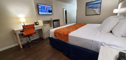 Habitación de hotel con cama, escritorio y TV. en THE PARAGON of Golden Isles en Brunswick