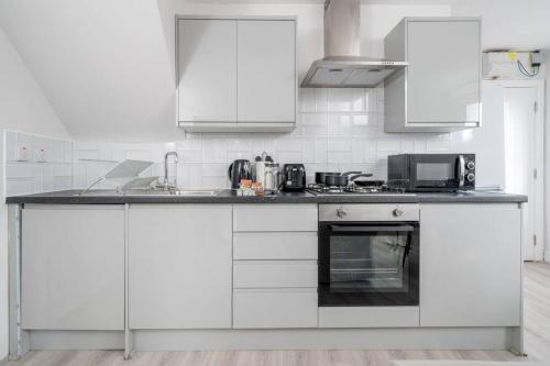a white kitchen with white cabinets and a stove at Trendy 2bed apartment in Brick Lane - 3rd Floor in London