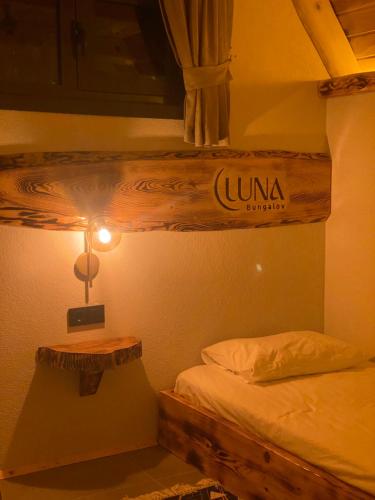 Luna Bungalov في ريزي: غرفة نوم بسرير وطاولة مع مصباح