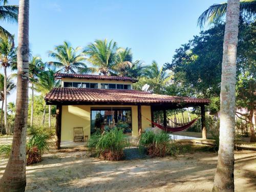 a house with a hammock in front of palm trees at Ampla casa em condomínio à beira d' agua in Caravellas
