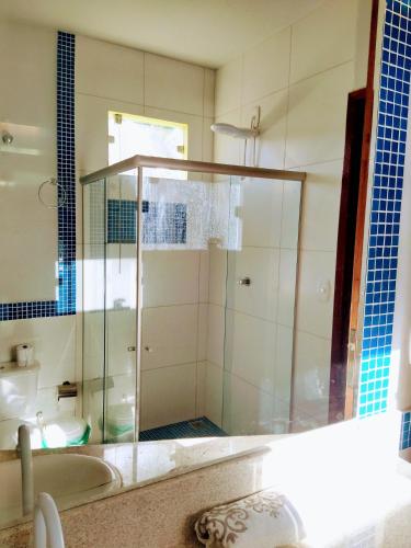 a bathroom with a glass shower with a tub at Ampla casa em condomínio à beira d' agua in Caravellas