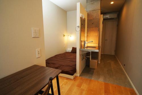 a small room with a bed and a table and a sink at Etcetera Niijima Nagisa Building - Vacation STAY 41890v in Niijimamura