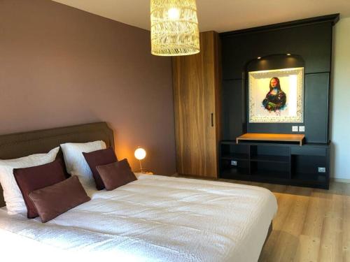a bedroom with a large white bed and a television at Le Clos des Marronniers n°1050 in Ecques
