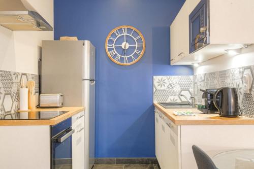 une cuisine avec un mur bleu et une horloge au mur dans l'établissement Caractère et Charmant en Hypercentre, à Lyon