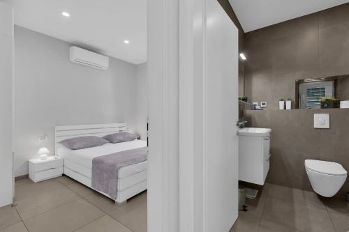 biała sypialnia z łóżkiem i toaletą w obiekcie City Center Apartment Dvor Kalalarga w Makarskiej