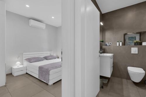 a white bedroom with a bed and a toilet at City Center Apartment Dvor Kalalarga in Makarska
