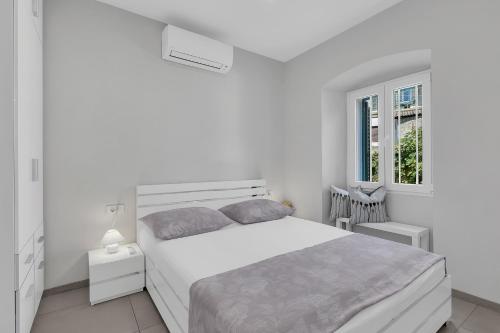 biała sypialnia z łóżkiem i oknem w obiekcie City Center Apartment Dvor Kalalarga w Makarskiej