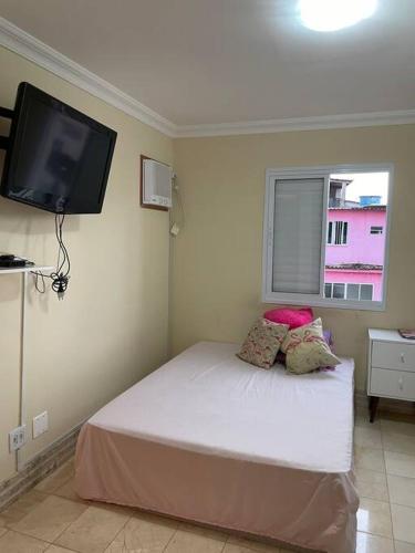 a bedroom with a bed with a tv on the wall at Apto mobiliado, 50 metros da praia. in Angra dos Reis