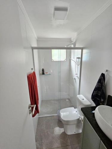 y baño con ducha, aseo y lavamanos. en Casa tranquila 500 metros da praia do campeche, en Florianópolis