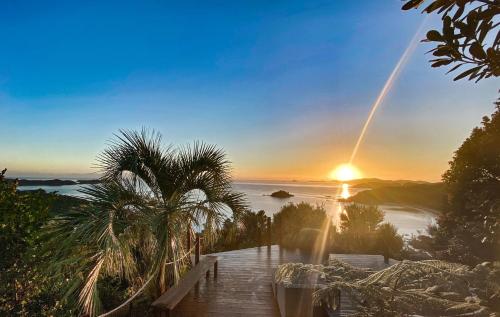 a view of the sunset from a deck with a palm tree at Te Koha Estate - Main Residence in Kaeo