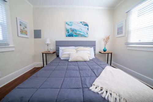 a large blue bed in a white room with two tables at Sea View, Flower Garden, A/c, W/d, Renovated in Hermosa Beach