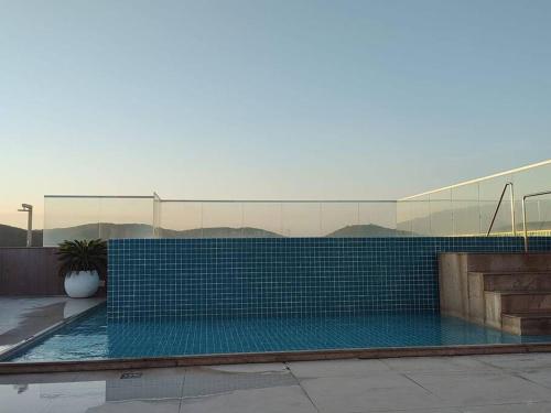 a swimming pool with blue tiles on the side of a building at Flat Luxo 102, hotel samba-cabo frio in Cabo Frio