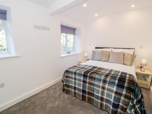 a bedroom with a large bed and two windows at The Cottage at Cromlech Manor Farm in Benllech