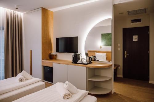 a hotel room with two beds and a desk with a television at Pensiunea Sylvania in Sovata