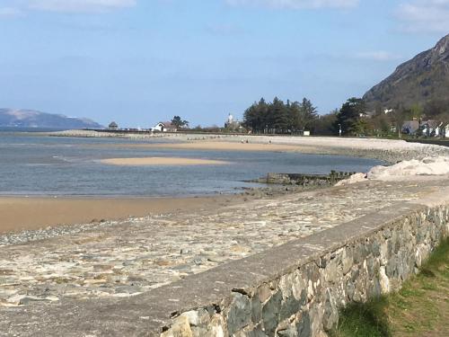 a beach with a retaining wall next to the water at Uwch-Y-Mor in Llanfairfechan